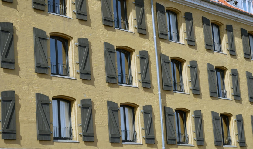 a tan building that has many windows and shutters