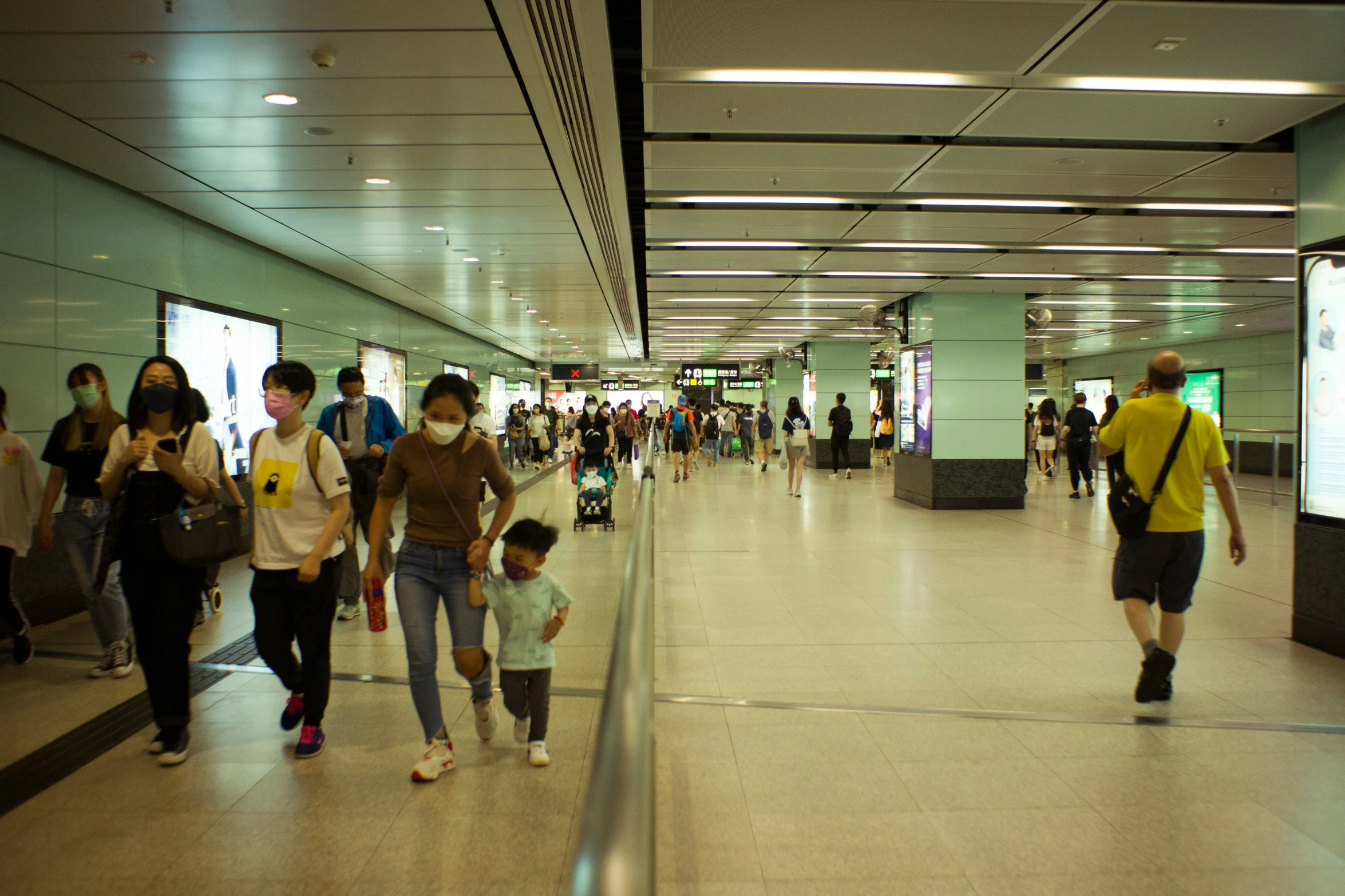 people are walking in an airport covered with people wearing masks