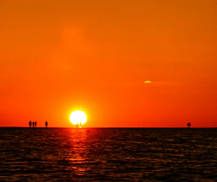 the sun rises behind the horizon over the ocean