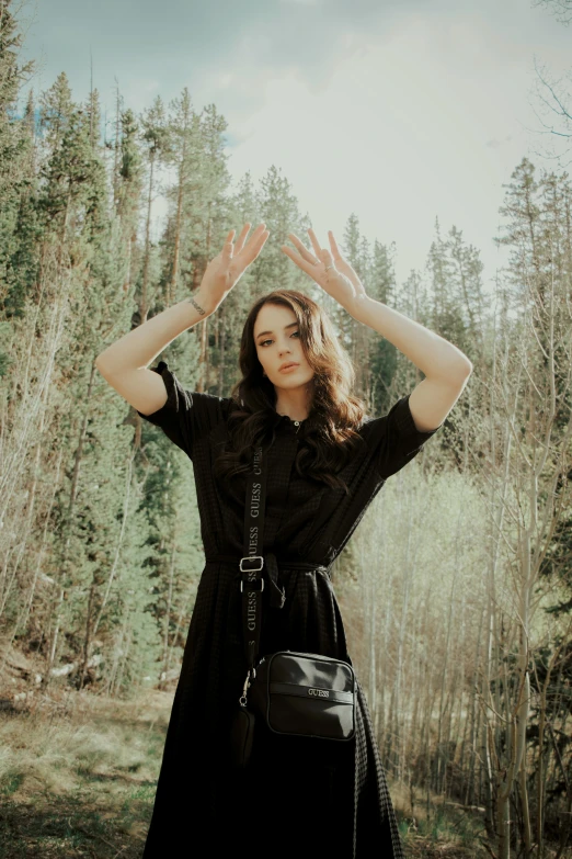 a young woman is standing on the forest floor holding her hands to her head