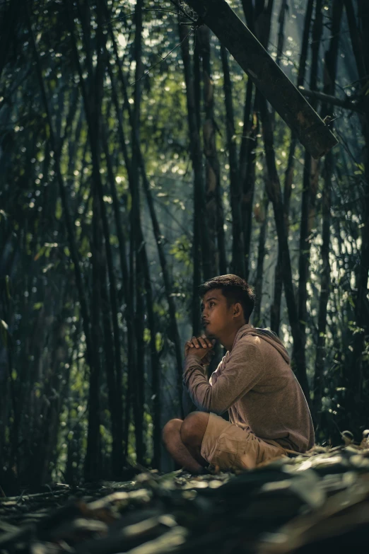 a man sitting on the ground in a forest