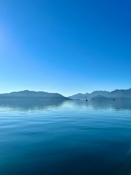 blue water with mountains in the distance near a shoreline