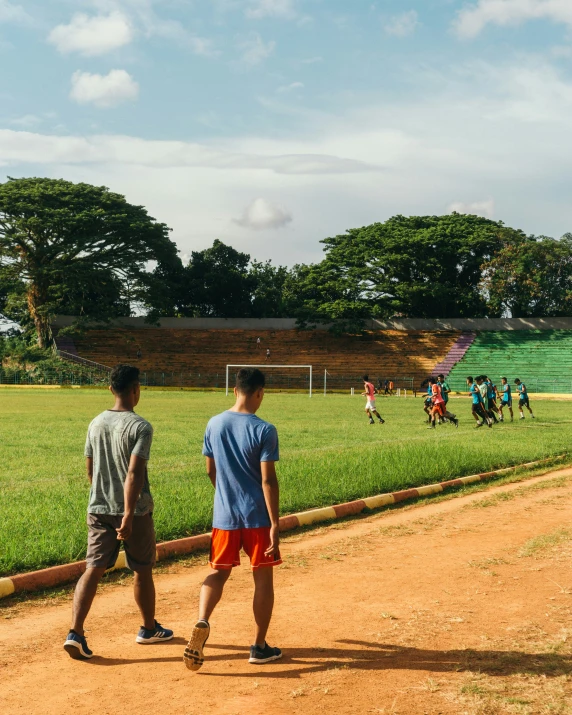 two men walking toward an outdoor soccer field