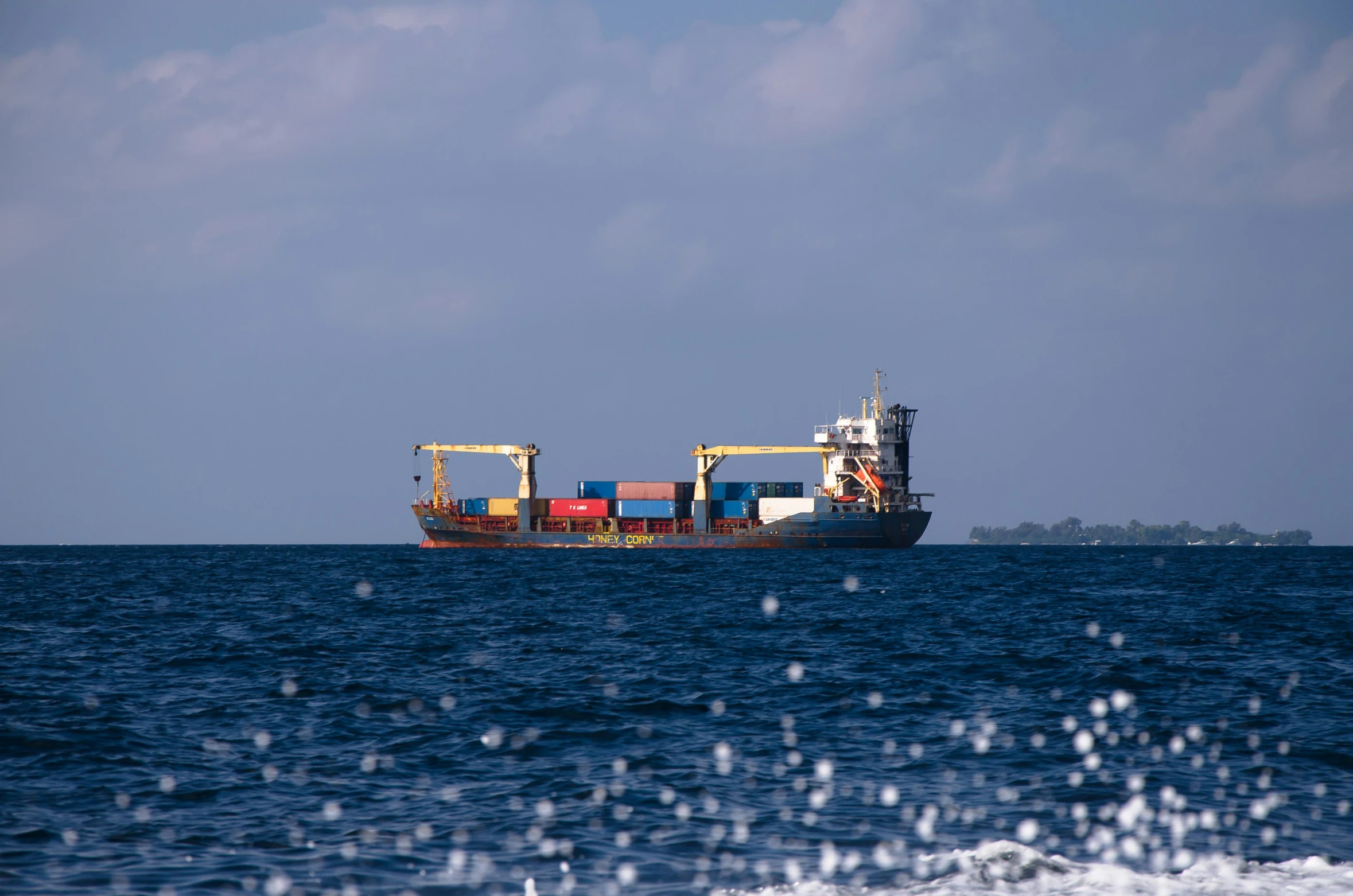 a boat is in the middle of the ocean, carrying a huge container