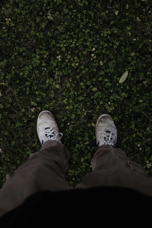 a top view of someone's feet and gray shoes on their legs