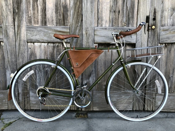 a green bicycle leaning against a wooden fence