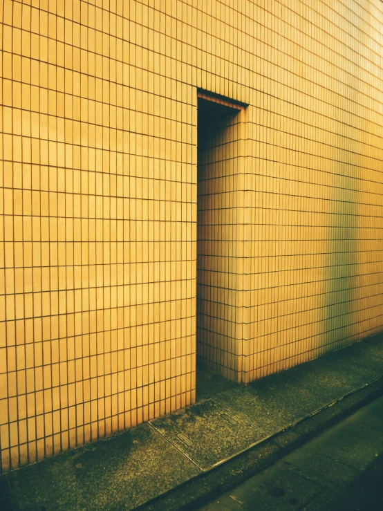 a wall with many squares covering it with green grass in front of it