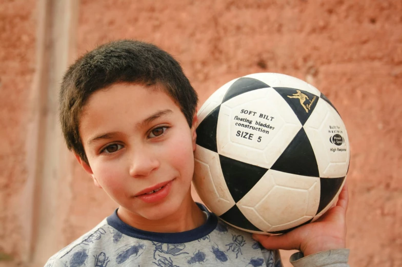 a boy holds a black and white soccer ball
