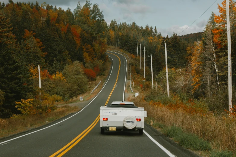 a truck is driving down the road in autumn