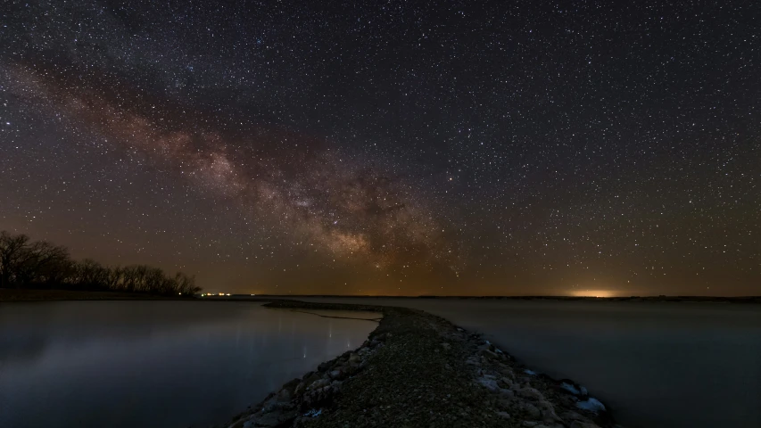 a dark sky filled with lots of stars above a body of water