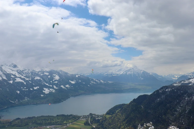 several people flying kites over a large lake