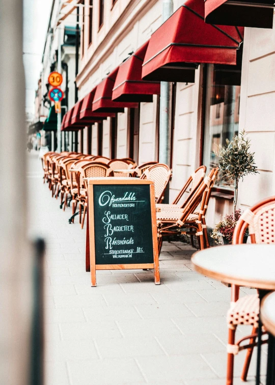 a restaurant sidewalk with a menu and chairs