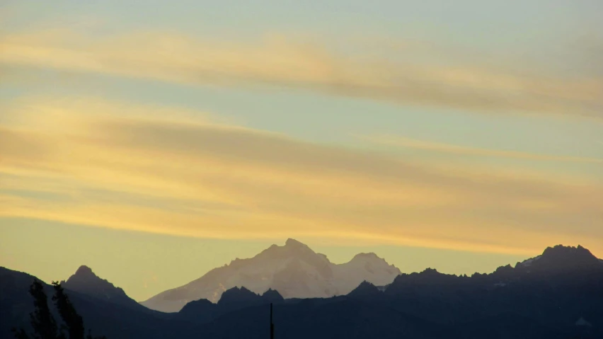 the silhouette of two mountains on a cloudy sky