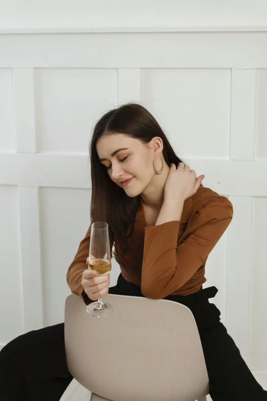 woman sitting at edge of chair holding glass of wine