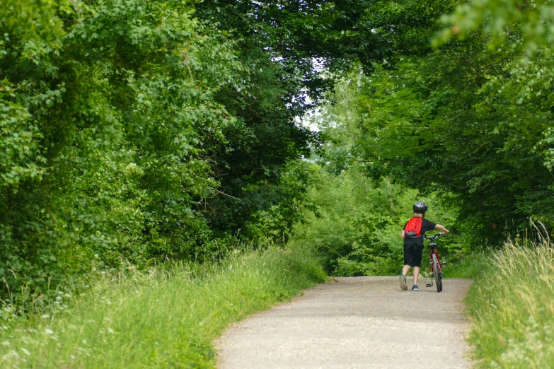 there is a man riding his bike down the trail