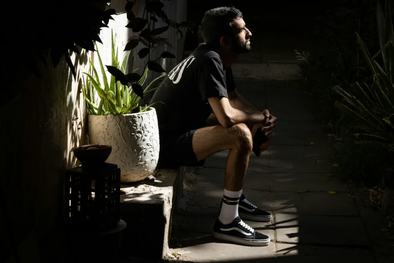 man sitting on brick ledge near potted plant with black and white socks