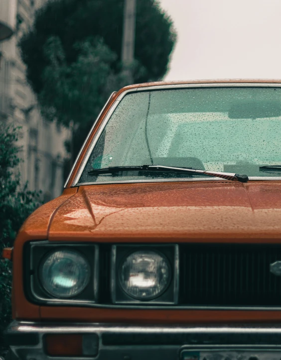 the front end of an orange car with its hood up