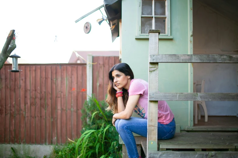 a woman in a pink shirt is sitting on a wooden step