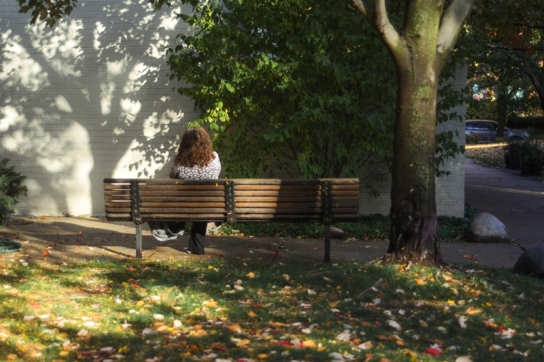 a woman sits on a park bench in the sun