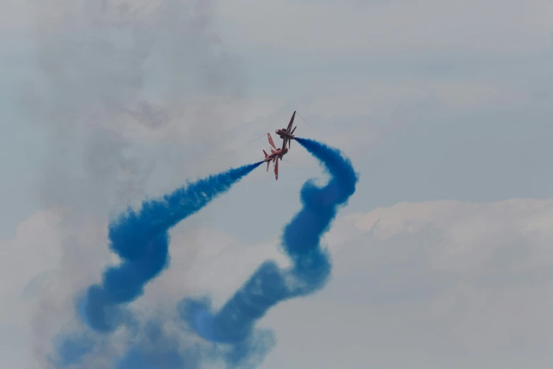 two planes flying and releasing blue exhaust for the next flight