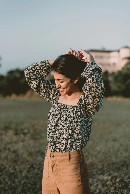 woman holding her hair in a field and smiling