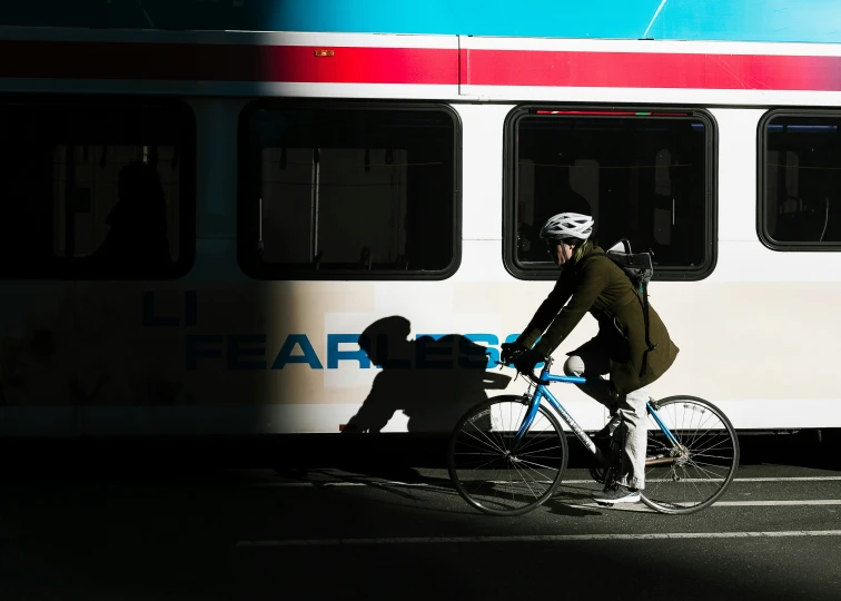 a man riding a bike while standing next to a white bus