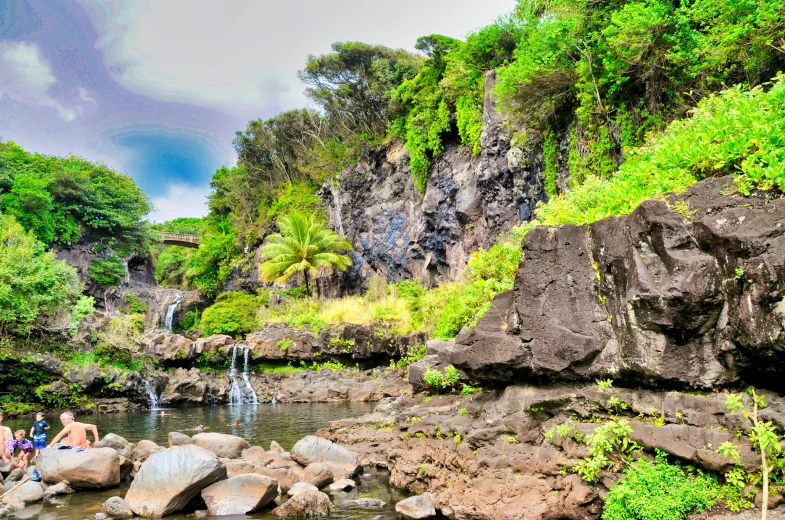 the people are standing on the rocks beside a waterfall