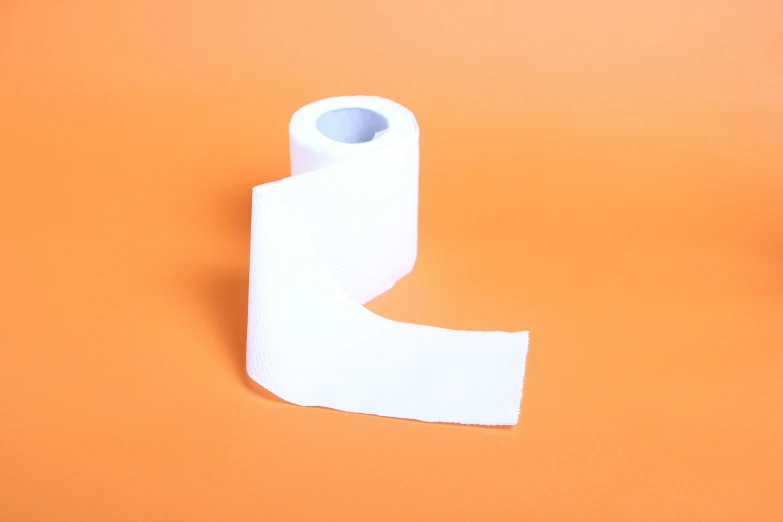 a roll of toilet paper is laying on the orange background