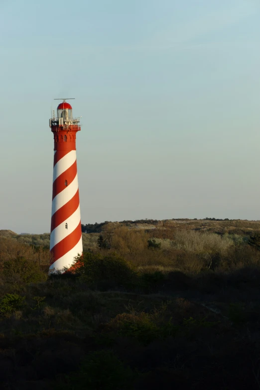 the large white and red lighthouse is out on the field