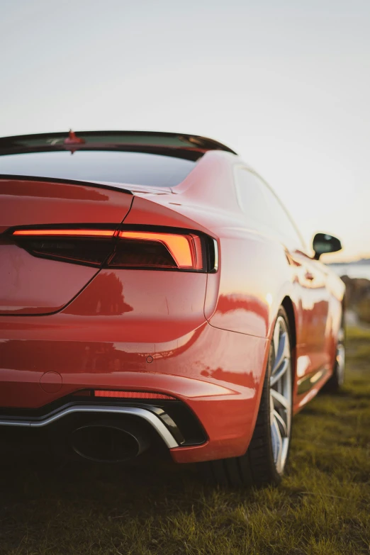 the back end of a red car parked in grass