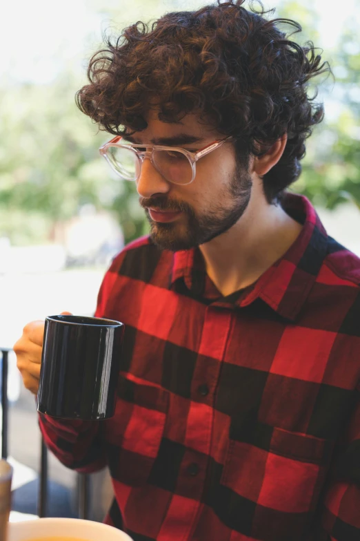 a man in plaid shirt holding a cup