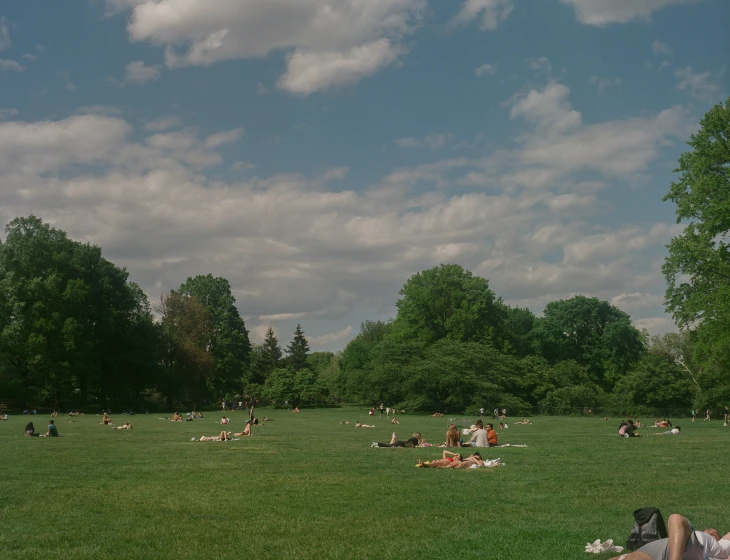 a lot of people sitting in a field, with many are laying down