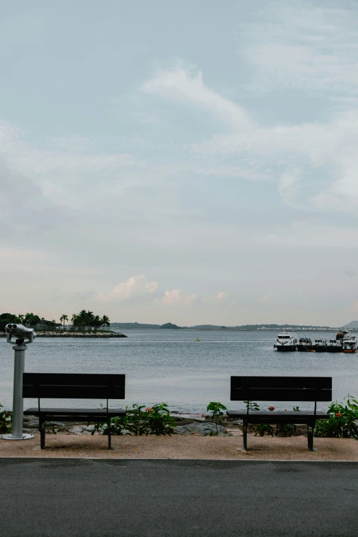 two benches in front of the ocean with boats