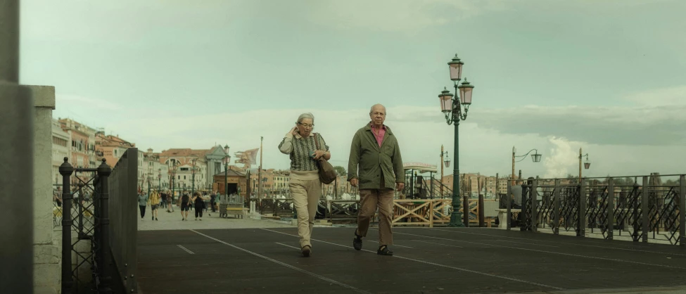 a man and woman are walking together along the bridge