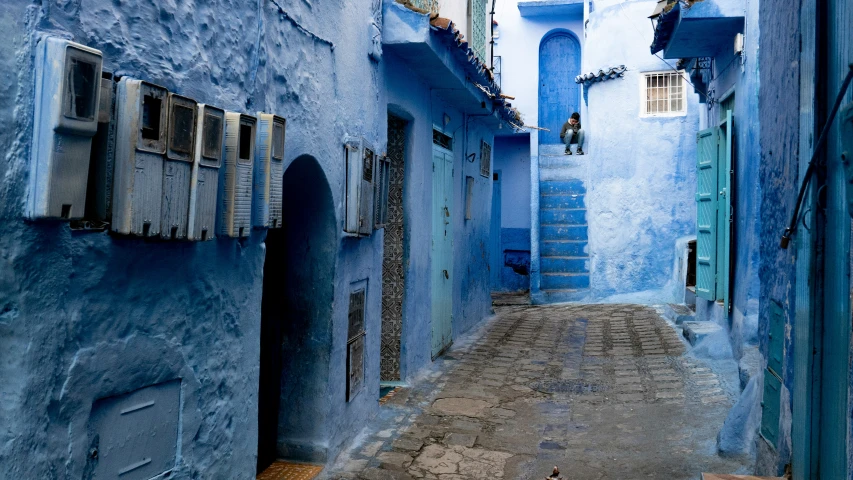 an alley way that has blue painted buildings