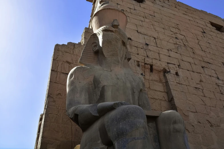 statue of egyptian god next to a tall building