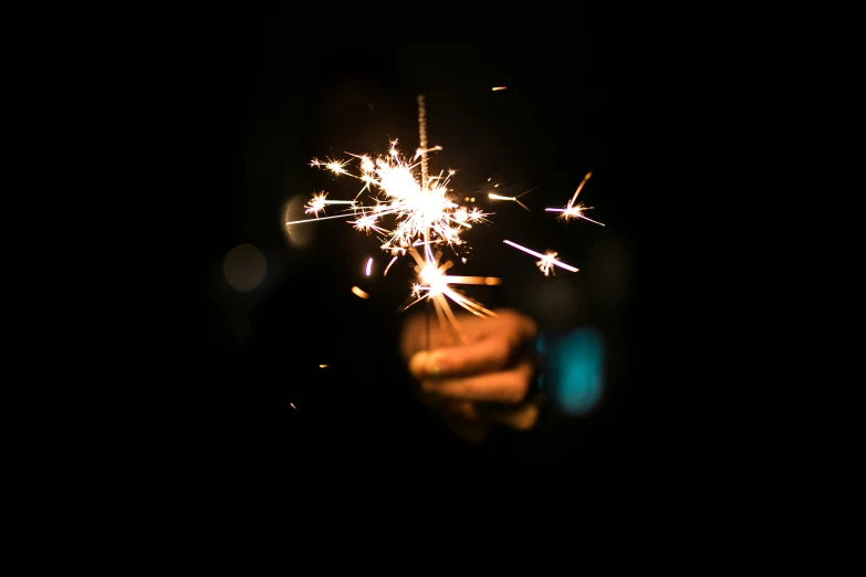 someone holds out their hand and holds onto a sparkler