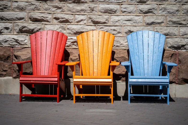 three adironds sitting side by side in brightly colored chairs