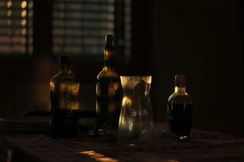 the bottles are on the table near the glass vase