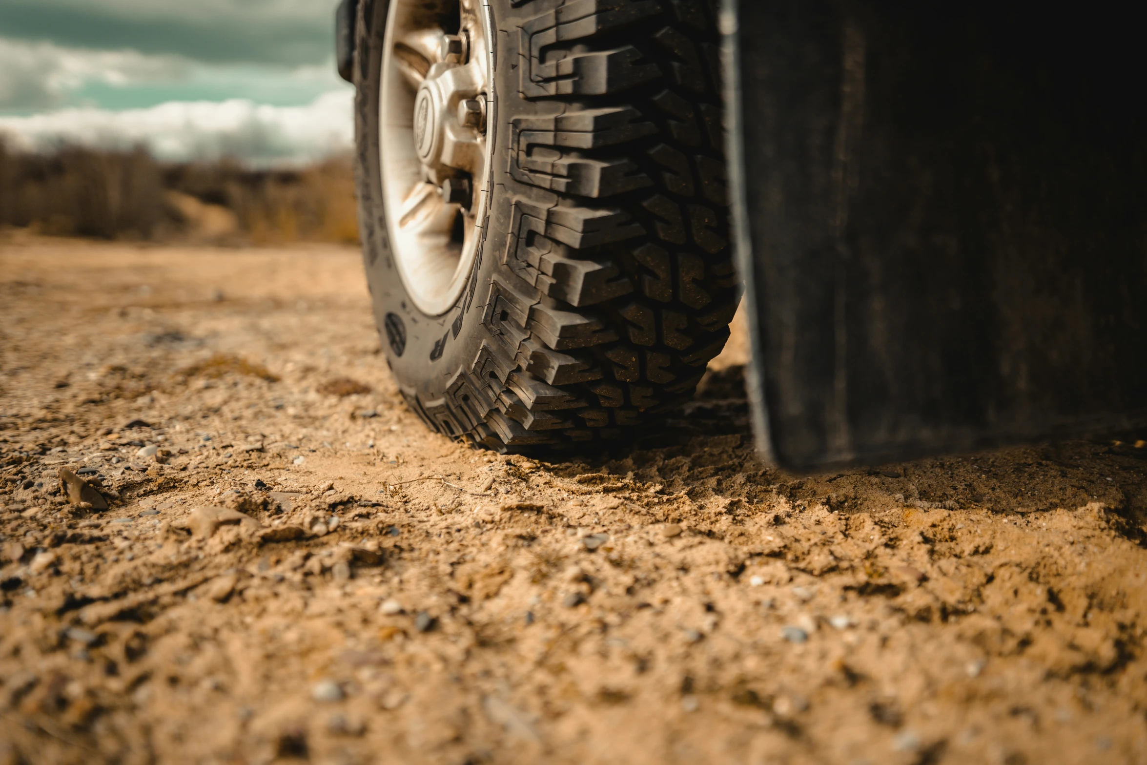 a large tire sits on the ground by a truck