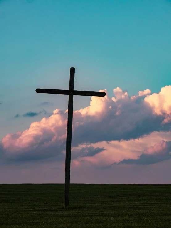 the cross is in the middle of the field with blue sky