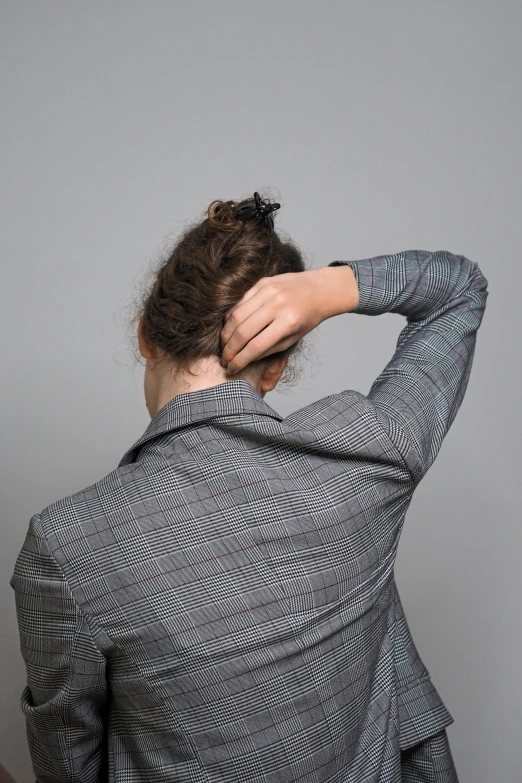 a girl with a tie and jacket is rubbing her hair