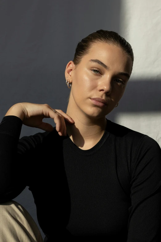 a woman with long brown hair and earrings sits