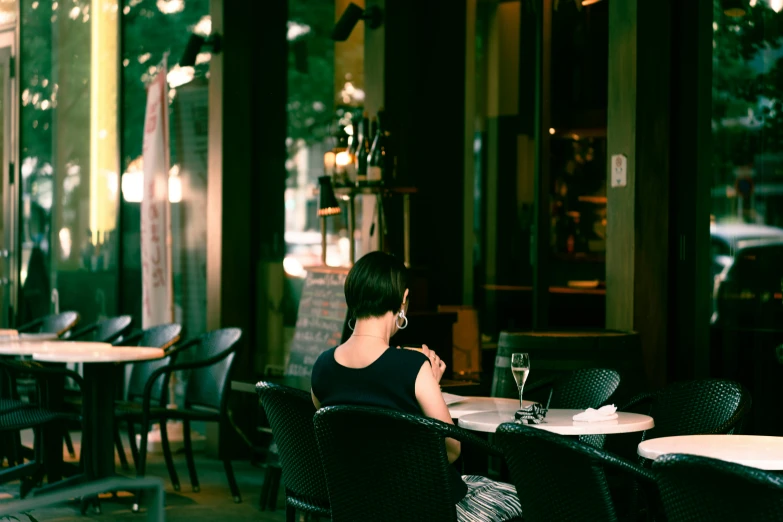 woman in black sitting at a table looking into glass windows