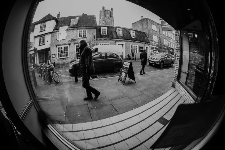 several people walk down a city sidewalk while one carries a large suitcase