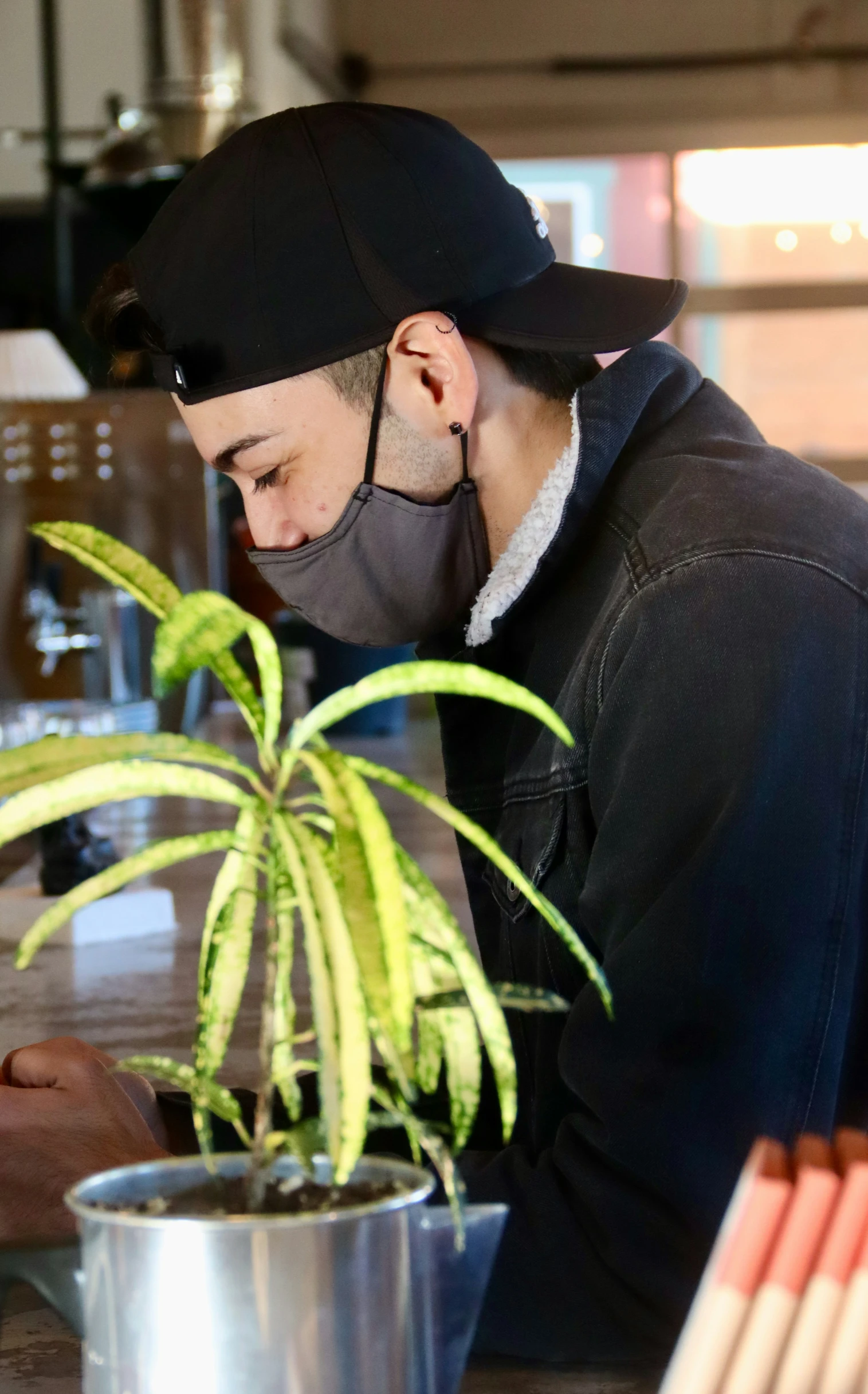 there is a man that is standing by the potted plant