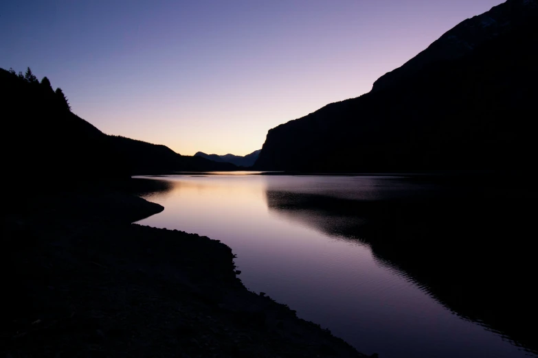 the sun is setting over a calm body of water