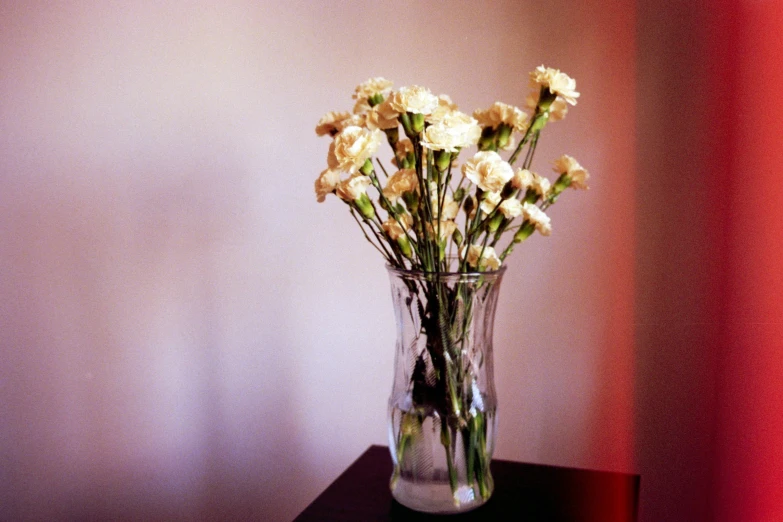 a vase of white roses sitting on a small table