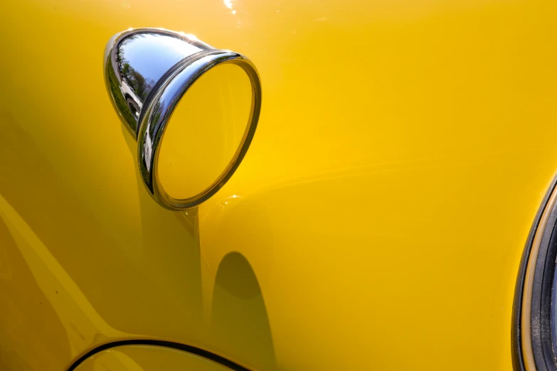 a close up view of the chrome hood of a yellow classic car