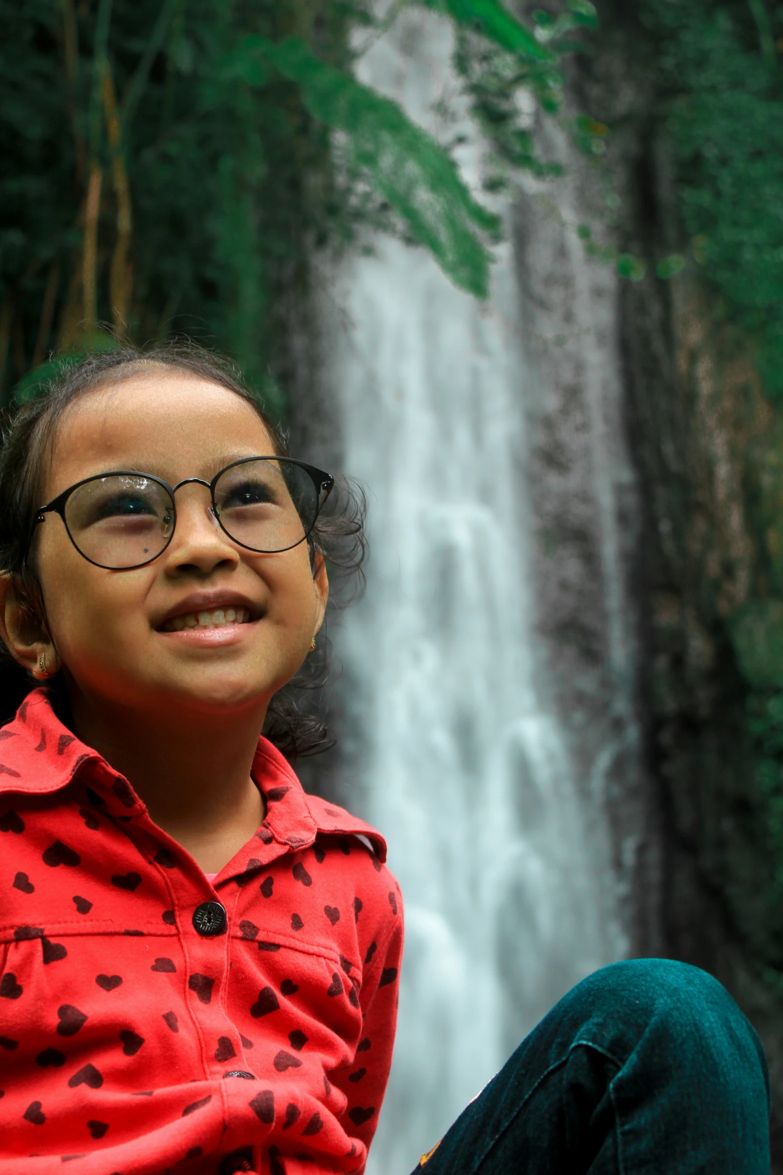 girl sitting in front of the waterfall with glasses